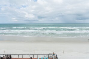 Une vue sur la plage avec un escalier descendant vers le sable, une rambarde et une personne se tenant en haut.