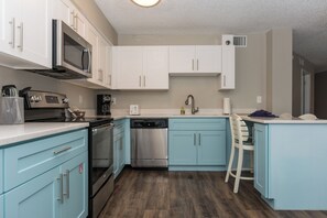 A modern kitchen with white cabinets, stainless steel appliances, and a blue countertop.