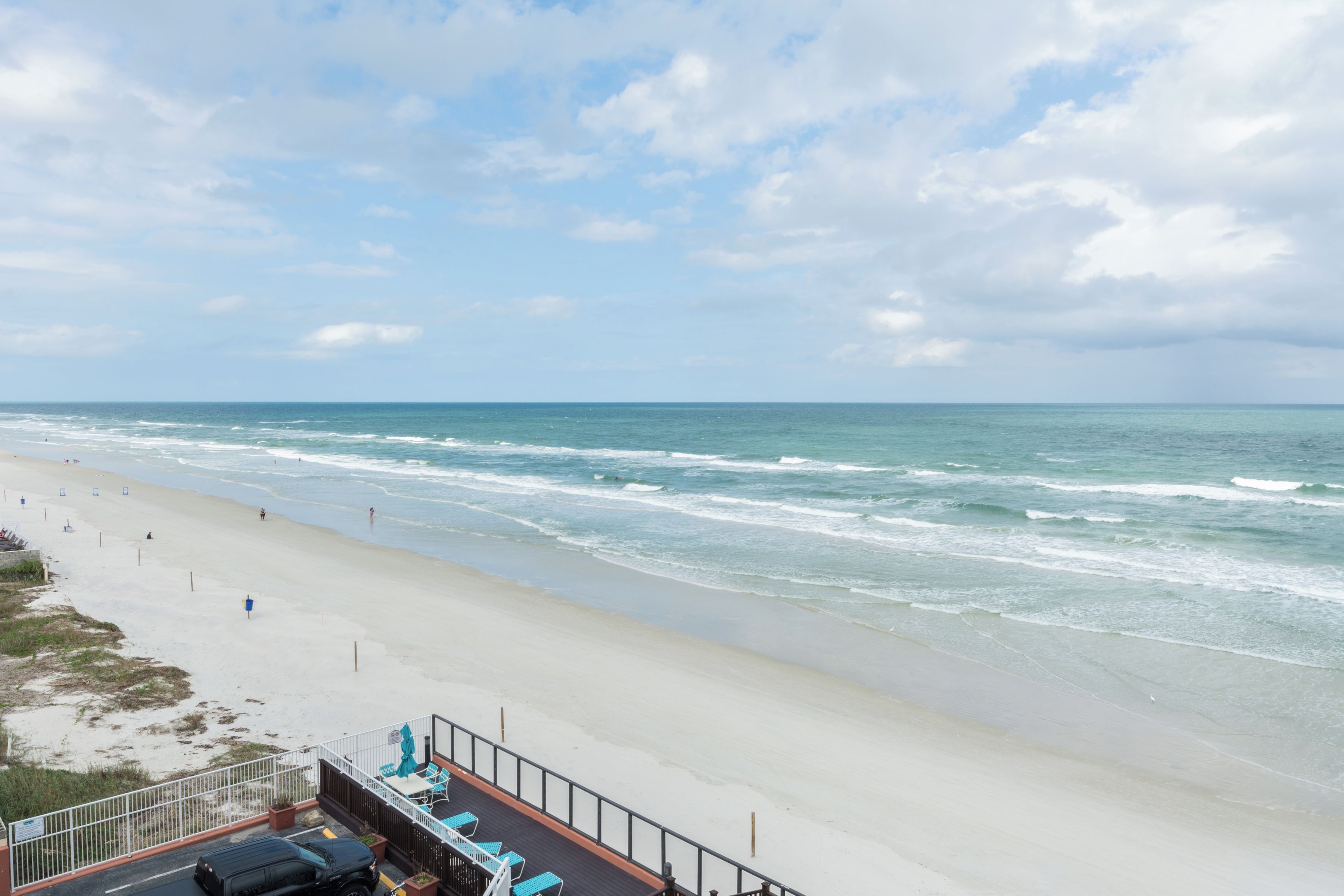 Blick auf einen Strand mit einem eingezäunten Bereich und Liegestühlen.