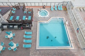 Un'area piscina sul tetto con diverse poltrone prendisole, una vasca idromassaggio e una piscina.