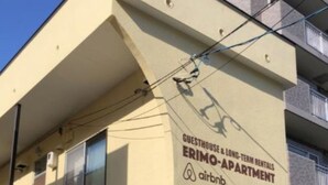 A building with a sign indicating it is a guesthouse and long-term rental, specifically an Airbnb apartment.