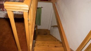 Eine Holztreppe mit Handlauf, Teppichstufen und einem grünen Handtuch an einem Wäscheständer.