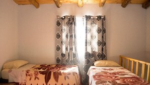 Ein Zimmer mit zwei Betten, Holz-Kopfteilen und Bettwäsche mit Blumenmuster.