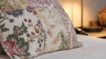 Una cama con un cojín estampado con motivos florales y una lámpara de noche.