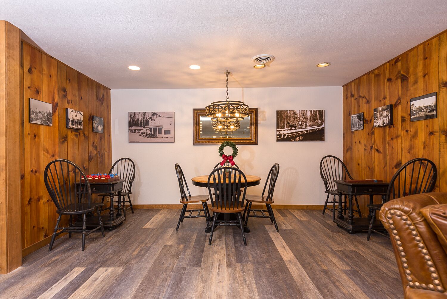 A dining area with a round wooden table, black chairs, and a chandelier.