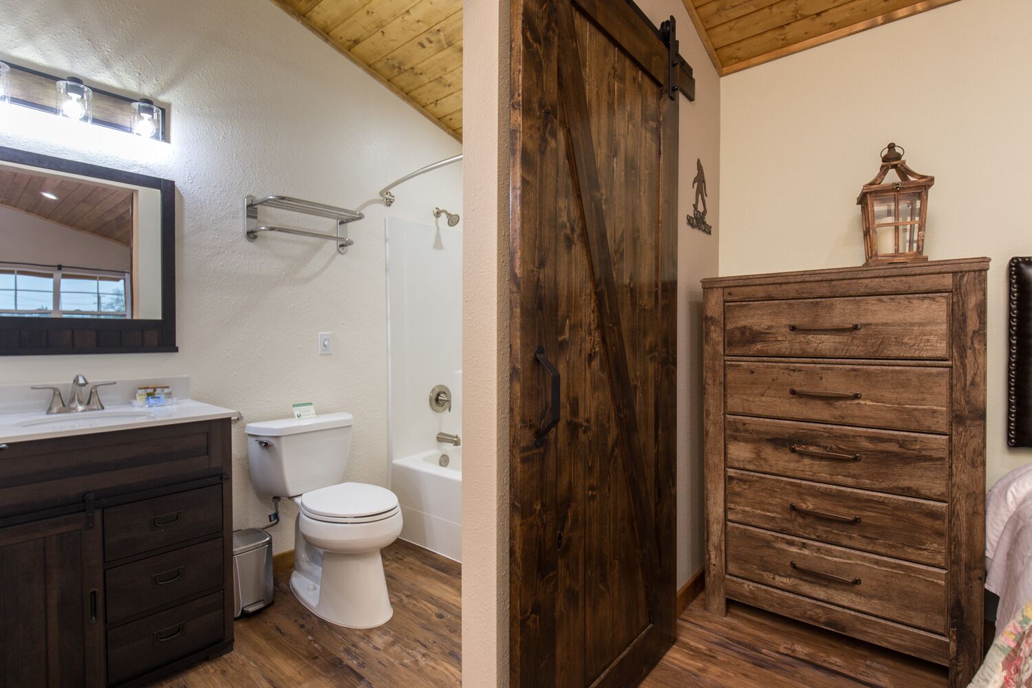 Een badkamer met een houten wastafelmeubel, een wit toilet en een bad.
