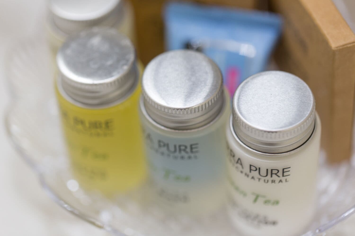 Three bottles of 'PURE NATURAL' skincare products in a clear glass container.