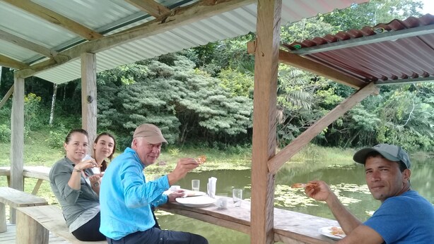 A wooden deck with a table and benches overlooking a pond with lily pads. - Wonderful View Cabins (Bijagua)
