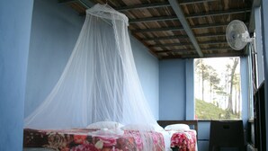 A room with two beds, one with a mosquito net, and a fan on the wall. - Wonderful View Cabins (Bijagua)
