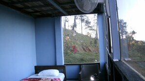 A room with a bed, a chair, and a window overlooking a hillside. - Wonderful View Cabins (Bijagua)