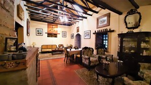 Uma sala de estar aconchegante com teto de madeira, lareira e área de jantar com mesa e cadeiras.