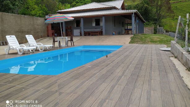 En swimmingpool med liggestole og en overdækket patio.
