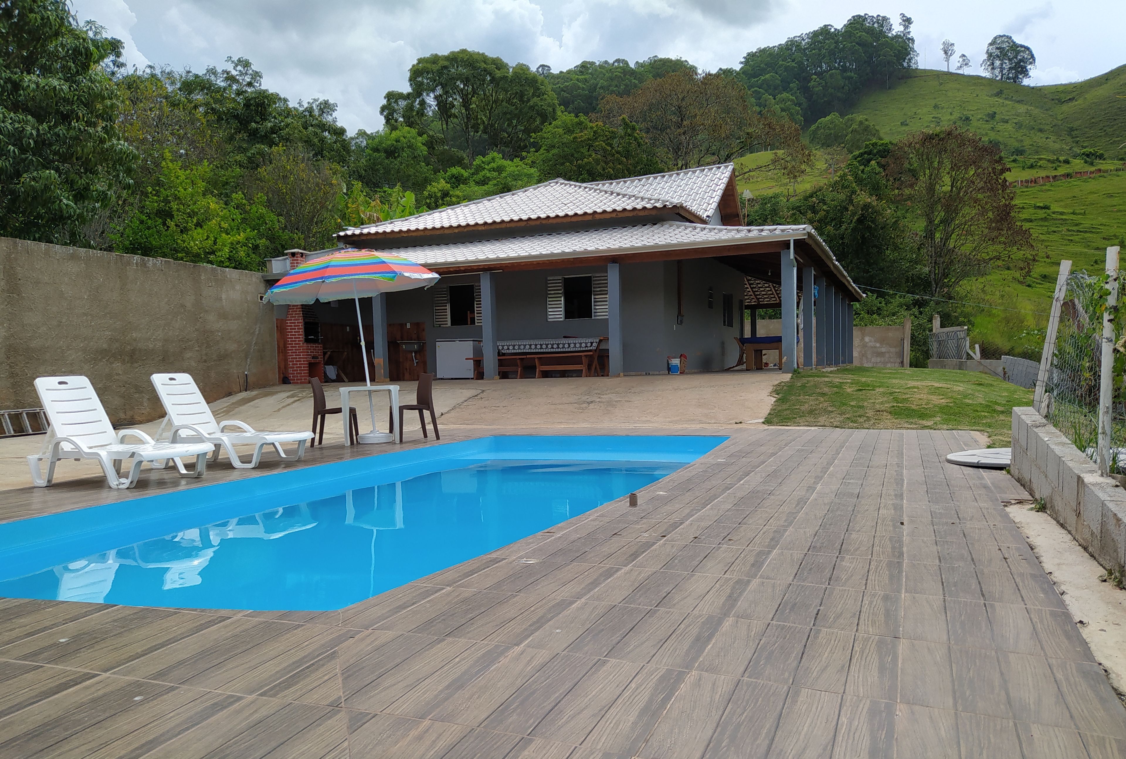 Une piscine avec des chaises longues et un espace patio couvert.