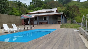 Une piscine avec des chaises longues et un espace patio couvert.