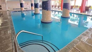 Ein Innenpool mit klarem Wasser, umgeben von Säulen mit Seestern-Dekorationen und einem gefliesten Boden.