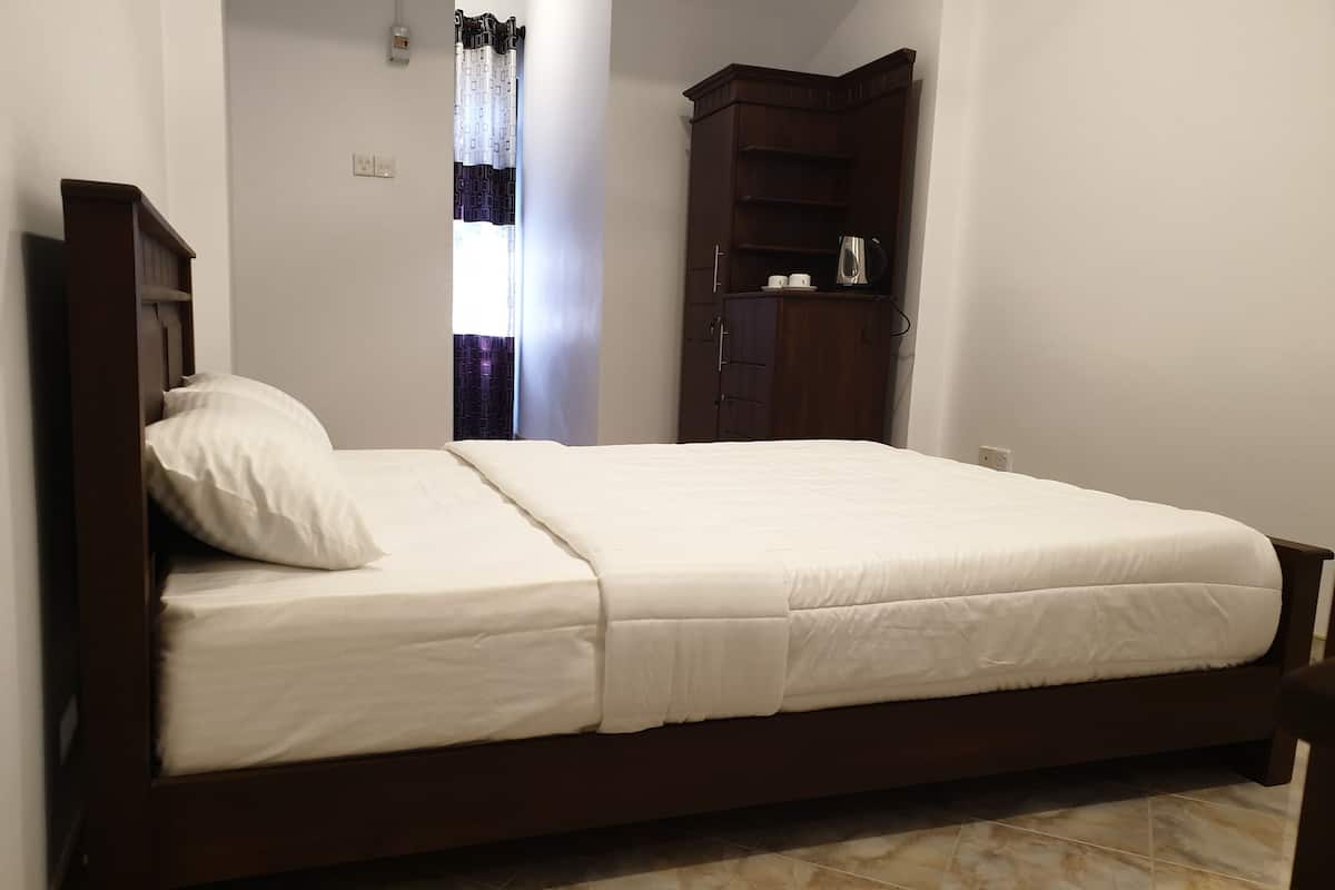Una cama individual con estructura de madera, colchón blanco y almohada a juego.