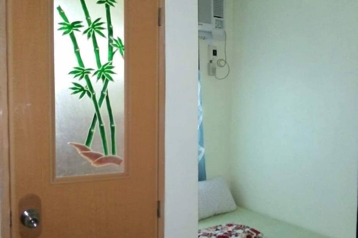 Une pièce comprenant un lit, un oreiller, une couverture et une porte ornée de motifs en bambou.