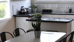 Une cuisine moderne avec une table et des chaises, une plante en pot et une fenêtre laissant entrer la lumière naturelle.