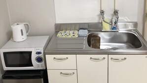 A compact kitchenette with a microwave, a small refrigerator, a sink, and a kettle. - Sapporo Apartment 203 (Sapporo)