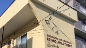 A building with a sign for "Guesthouse & Long-Term Rentals" and "Erimo Apartment" with an Airbnb logo. - Sapporo Apartment 205 (Sapporo)