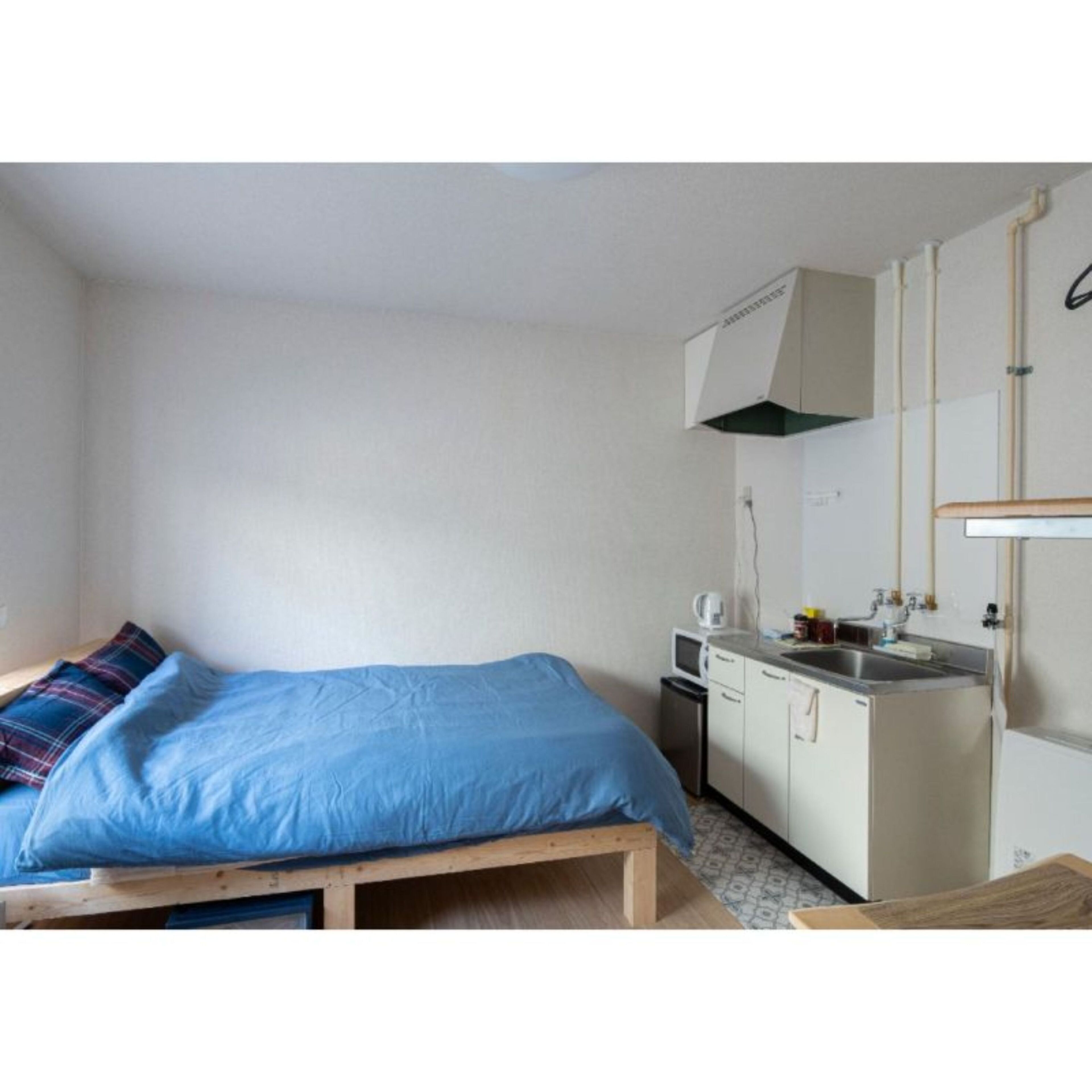 Une petite pièce compacte comprenant un lit, une kitchenette et une salle de bain.