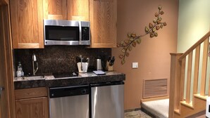 Une cuisine dotée de meubles en bois, d’appareils électroménagers en acier inoxydable, de plans de travail en granit et d’un élément décoratif mural.