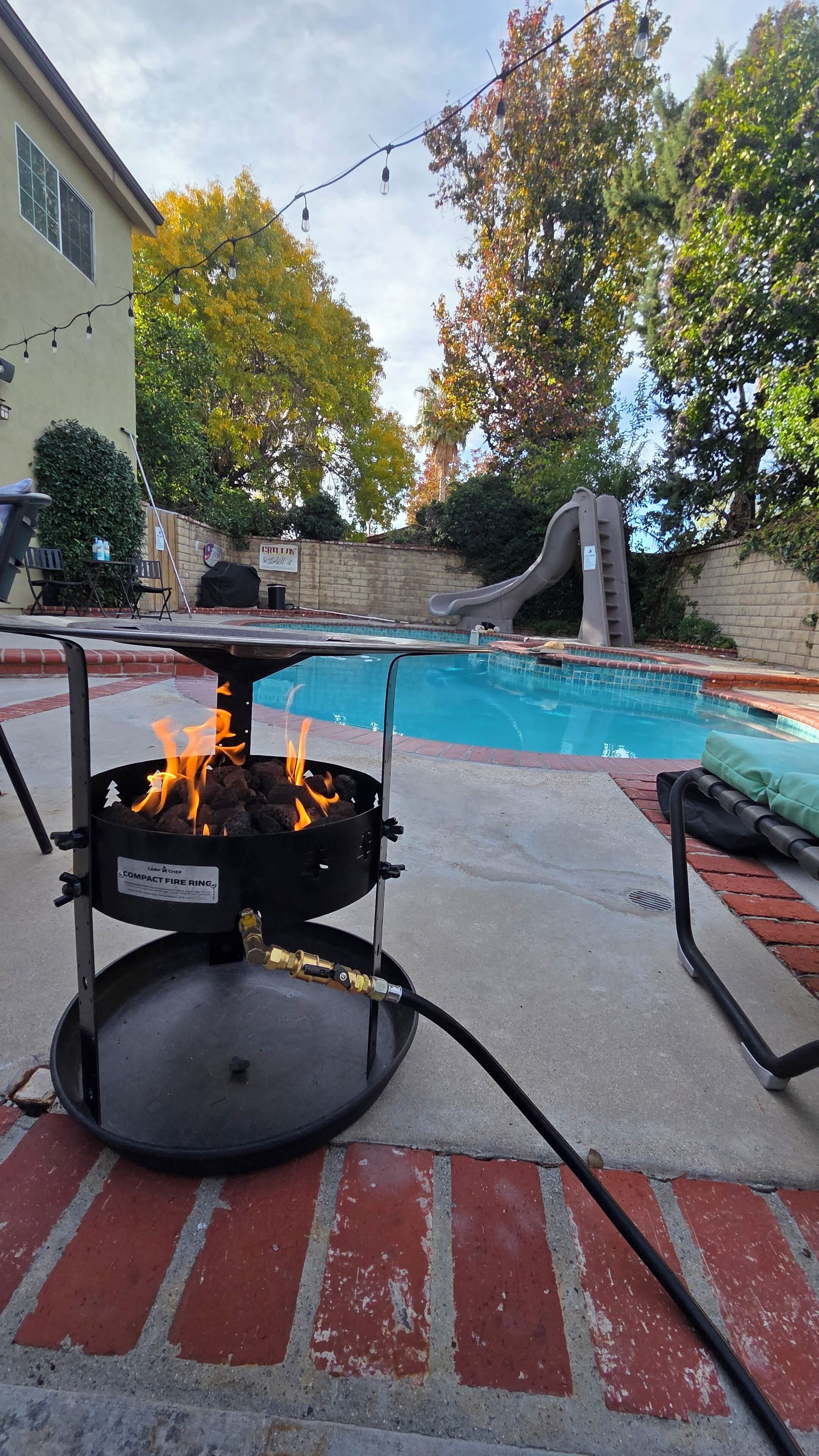 Un jardin avec une piscine, un barbecue et un toboggan.