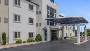 Un hôtel moderne doté d’une entrée couverte, de nombreuses fenêtres et d’une enseigne indiquant qu’il fait partie de la chaîne Amerisuites.