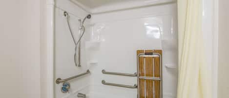 Una bañera con barras de apoyo y un panel de madera para asistencia.