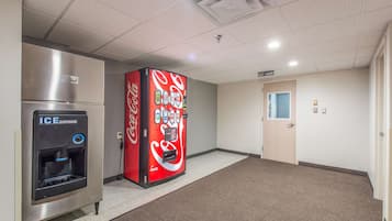 Corredor com dispensador de gelo, máquina de refrigerantes Coca-Cola e área de lavanderia para hóspedes.