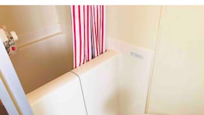 A bathroom with a bathtub, a toilet, and a shower curtain. - Sapporo Apartment 0 (Sapporo)