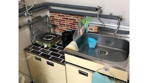 A kitchen with a gas stove, a sink, and a tiled backsplash. - Sapporo Apartment 0 (Sapporo)