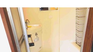 A small, compact bathroom with a toilet, sink, and shower area. - Sapporo Apartment 1 (Sapporo)