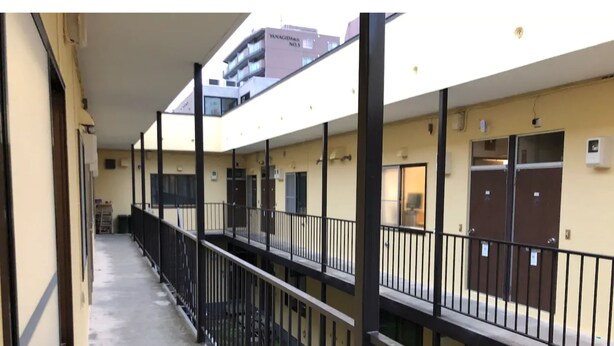 A multi-story building with a covered corridor, balconies, and doors. - Sapporo Apartment 1 (Sapporo)