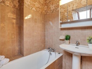 A bathroom with a bathtub, a sink, and a mirror. - Ty Mam Goz by Interhome (La Trinité Sur Mer)