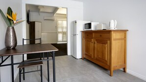 A compact kitchen with a wooden cabinet, a white refrigerator, a microwave, and a coffee maker. - Bellarine Spa Wellness & Retreat (Portarlington)