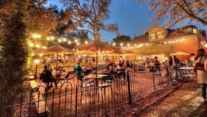 An outdoor dining area with tables and chairs, surrounded by trees and a brick building. - The St. Charles Guest House, lovely historic home, fun for families and groups (St. Charles)