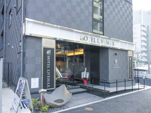 Un hotel moderno con fachada de vidrio, una entrada destacada y un letrero que dice "HOTEL L'VEMAX".