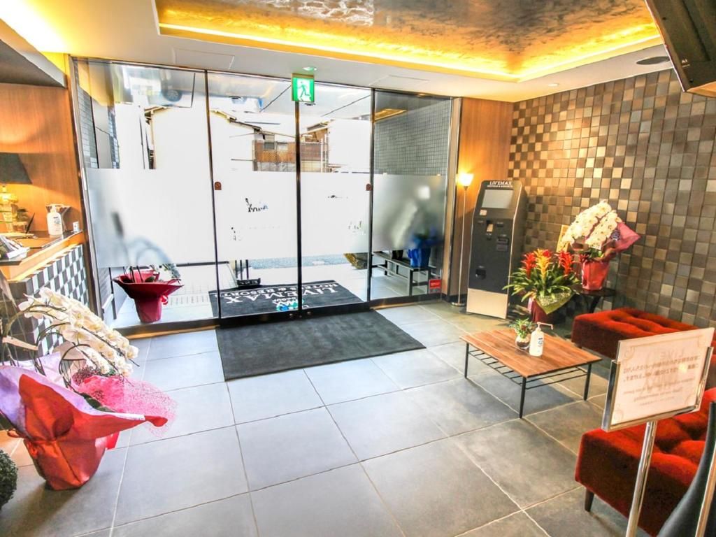 A hotel lobby with a reception desk, a seating area with red chairs, a coffee table, and a wall-mounted phone.