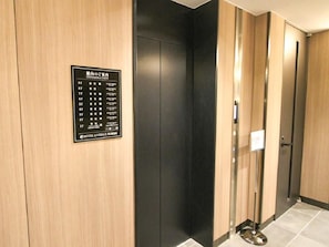 Un ascensor de hotel con un cartel indicador en la pared, que muestra los números de los pisos y el nombre del hotel.