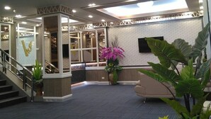 A spacious lobby with a central staircase, a reception desk, and a large circular light fixture on the ceiling. - Grand Visanu Hotel (Nakhon Sawan)