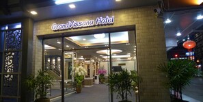 De entree van Hotel GrandVissanu met een modern ontwerp, glazen deuren en binnenshuis planten.