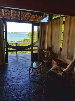 A room with a view of the sea, a hammock, a chair, and a small table. - Tudo Azul Internacional (Búzios)