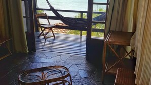 A room with a view of the sea, a hammock, and a wooden chair. - Tudo Azul Internacional (Búzios)