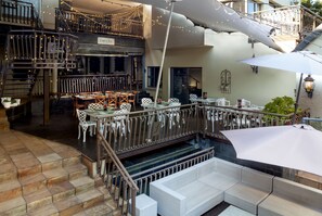 A multi-level restaurant with outdoor seating, a staircase, and string lights. - InnJoy Boutique Hotel (Centurion)