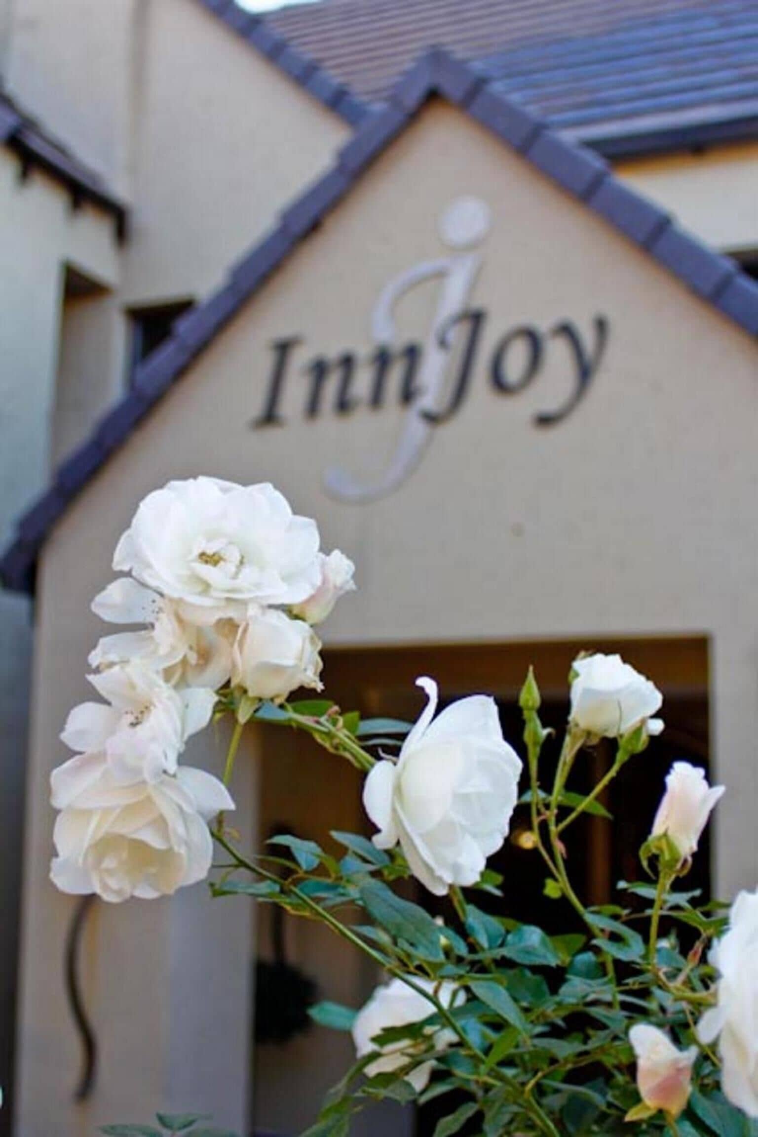 A building with the sign "InnJoy" and white roses in front.