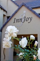 A building with the sign "InnJoy" and white roses in front.