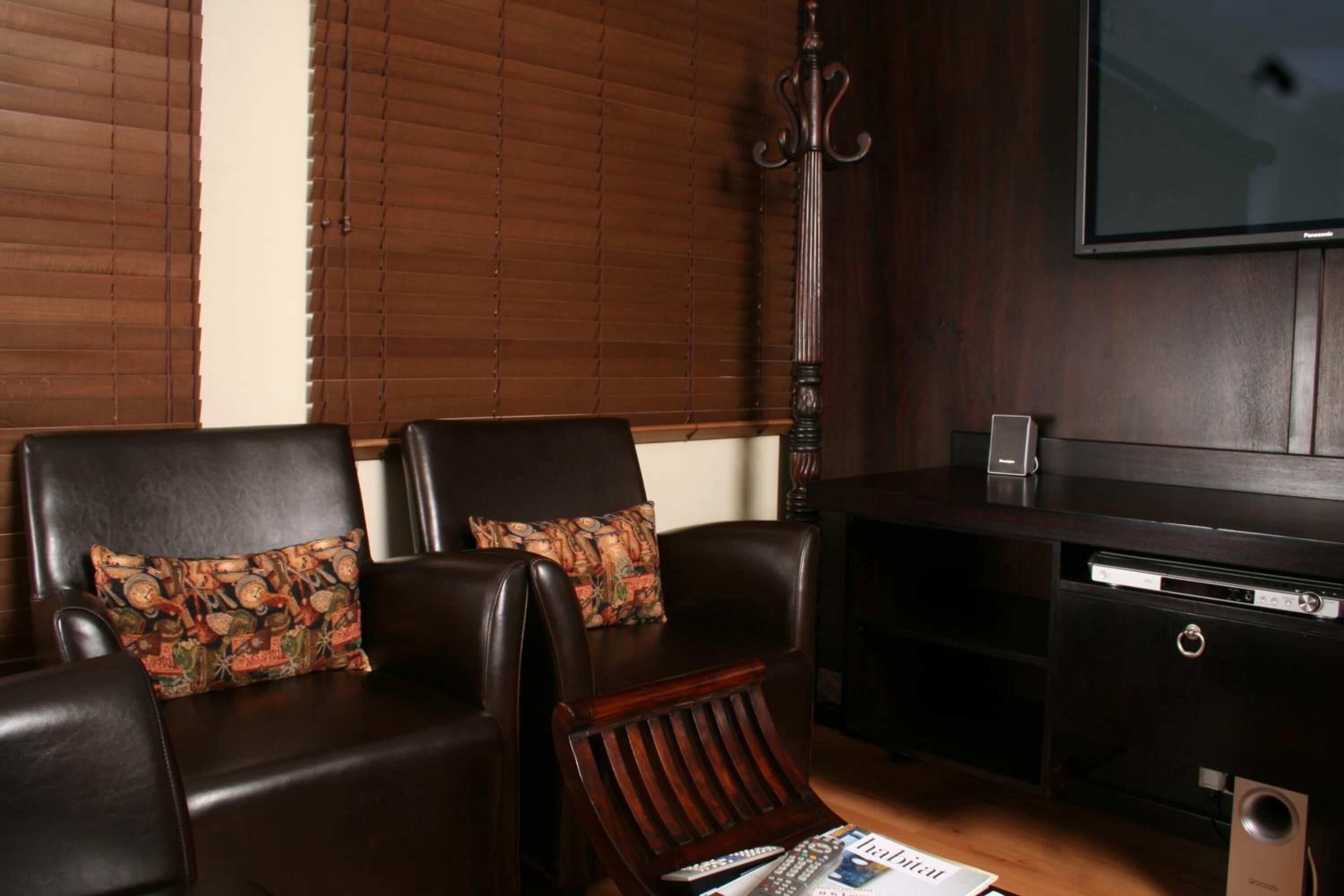 Una sala de estar con sillones de cuero, una mesa de centro de madera, un televisor de pantalla plana y un sistema de sonido.