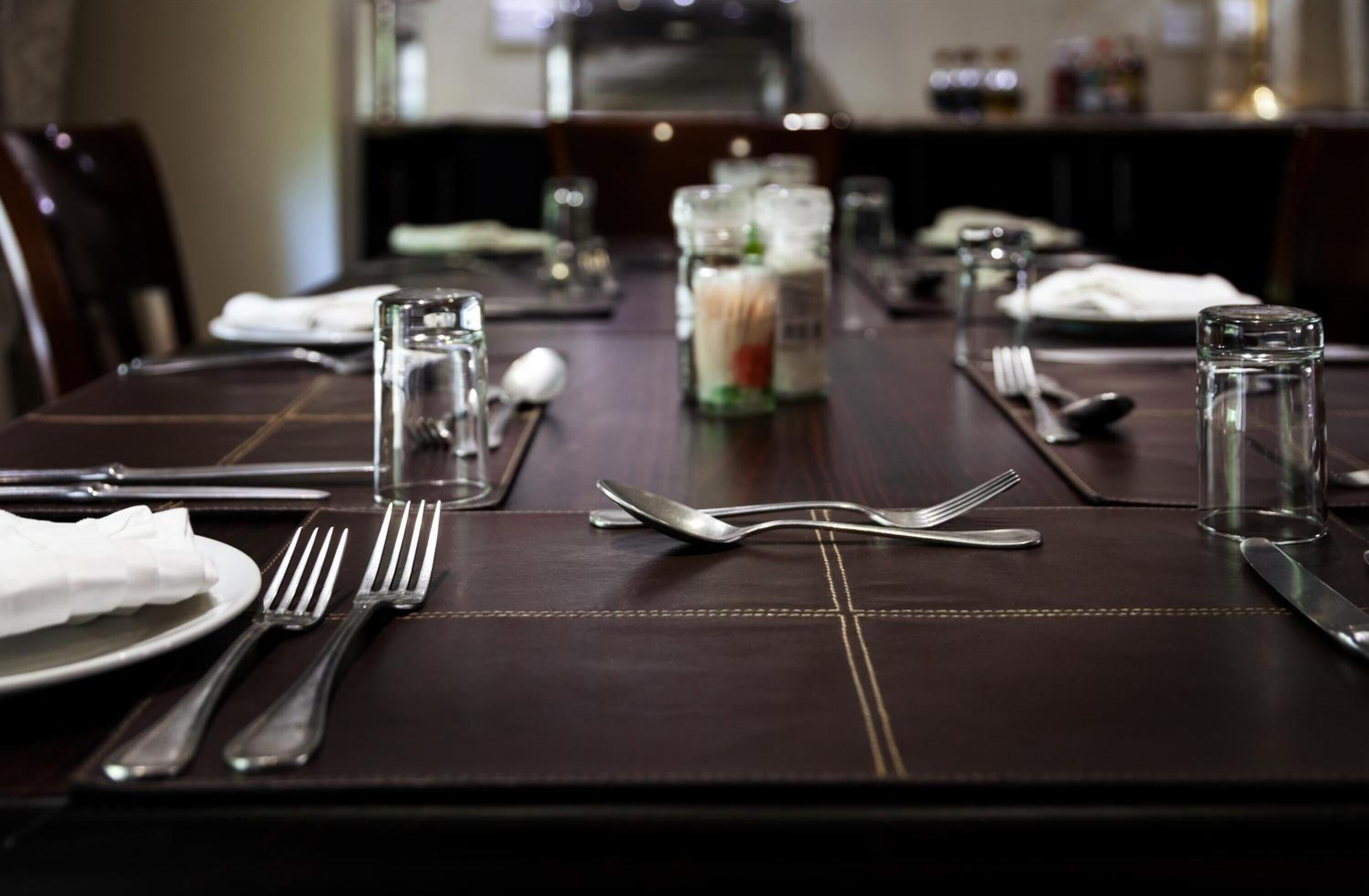 A dining table set with cutlery, glasses, and condiments, indicating a formal dining arrangement.