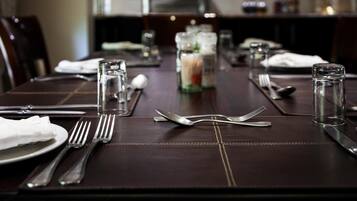A dining table set with cutlery, glasses, and condiments, indicating a formal dining arrangement.